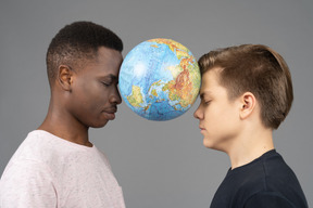 Two young men holding the earth globe between their foreheads