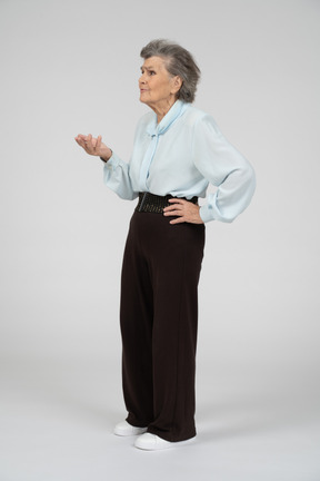 Three-quarter view of an old woman gesturing in question
