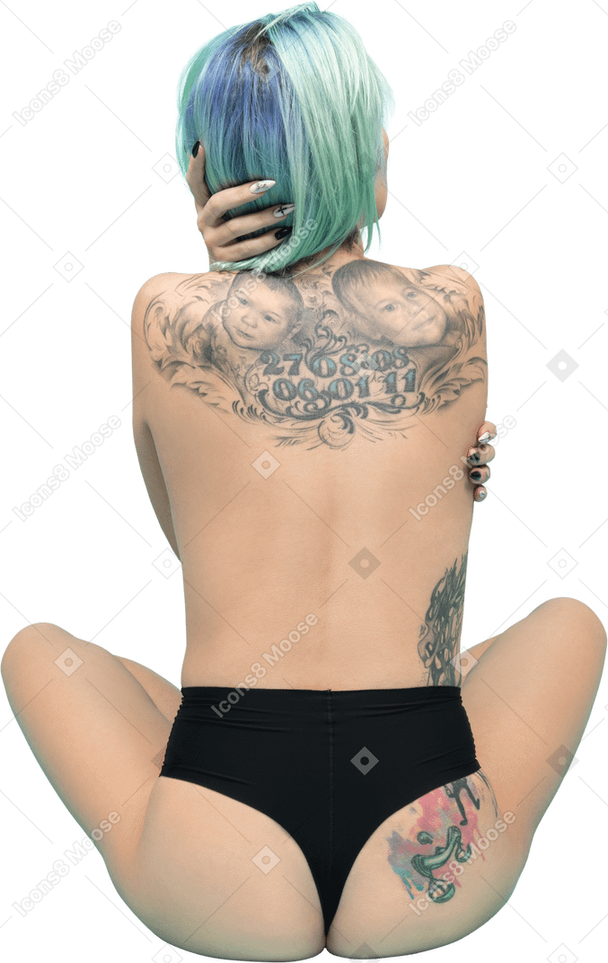 Donna tatuata in bikini nero che si siede indietro alla macchina fotografica