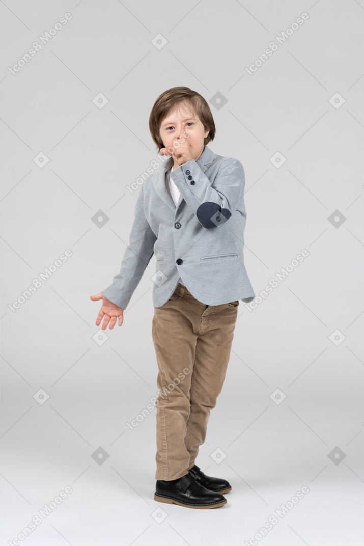 A young boy dressed in a suit pointing up