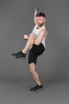 Expressive young man exercising with dumbbells