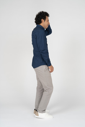 Side view of a man in casual clothes scratching head