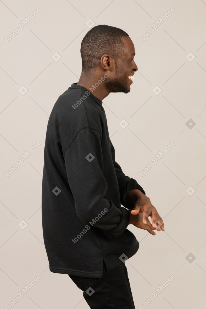 Side view of young man smiling and gesturing