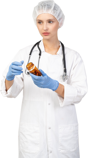 Vista frontal de una joven doctora abriendo un frasco de pastillas