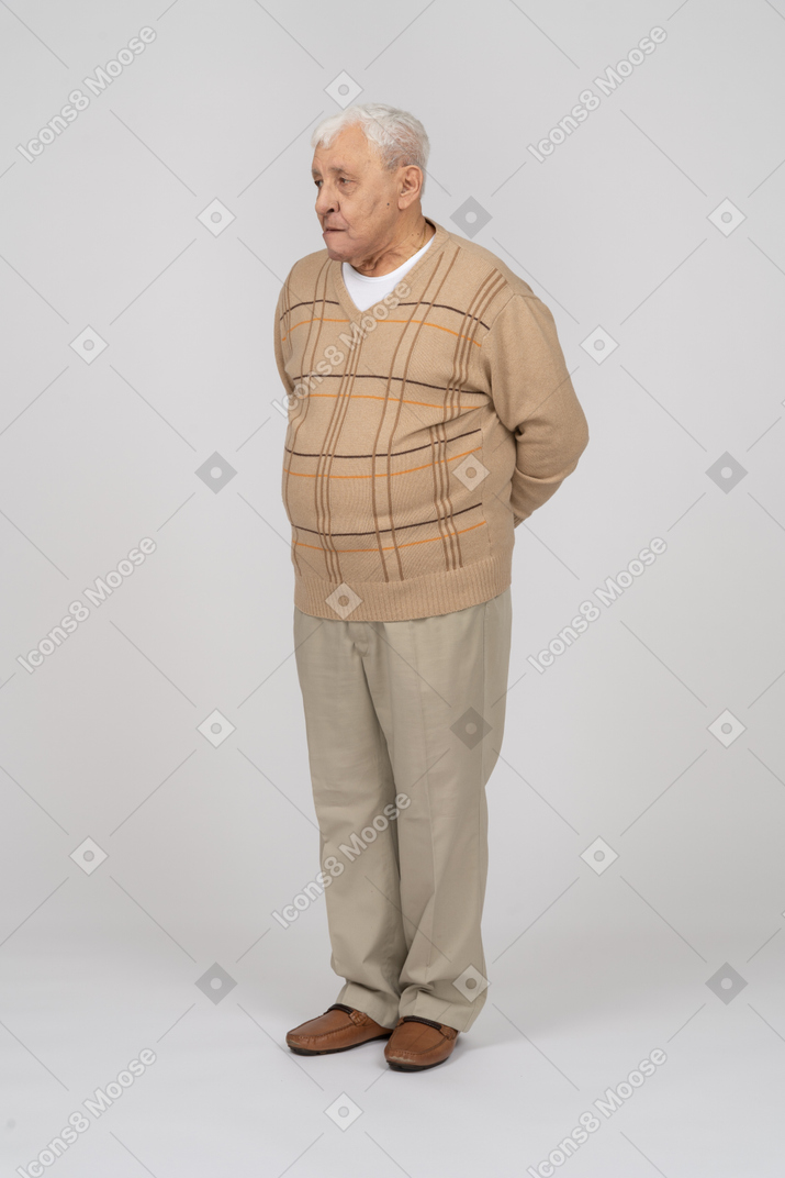 Front view of an old man in casual clothes standing with hands behind back