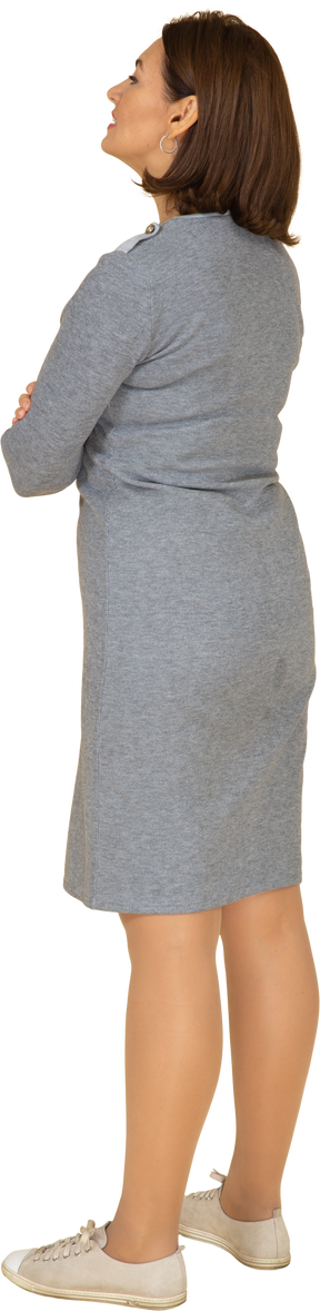 Vista laterale di una donna in abito grigio in piedi con le braccia incrociate