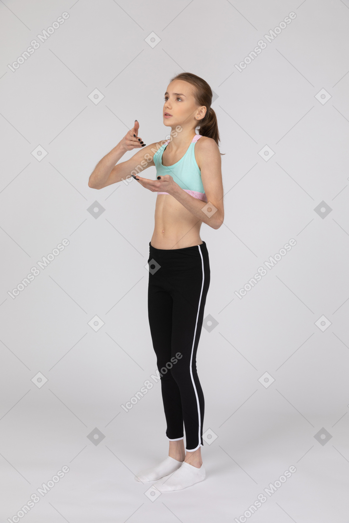 Vista de três quartos de uma adolescente em roupas esportivas levantando a mão e discutindo