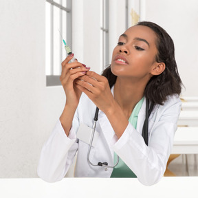 A woman in a white coat is holding a syringe