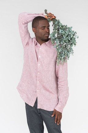 Good looking young man holding green branches