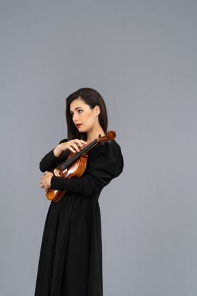 Three-quarter view of a young lady in black dress holding the violin
