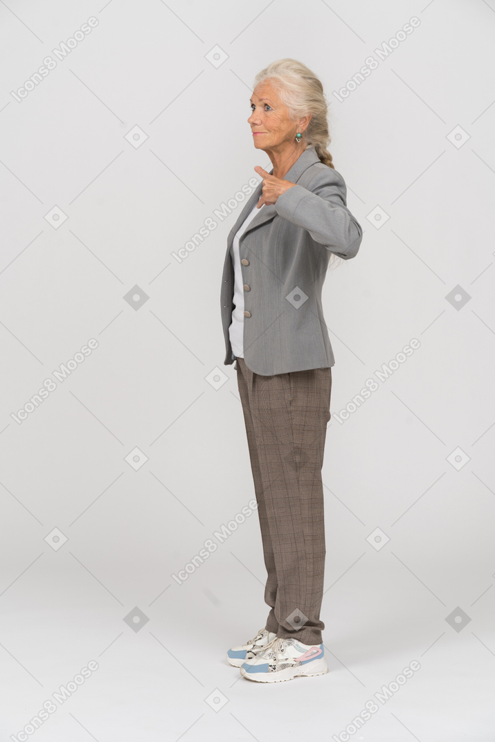 Vista lateral de una anciana en traje apuntando con un dedo