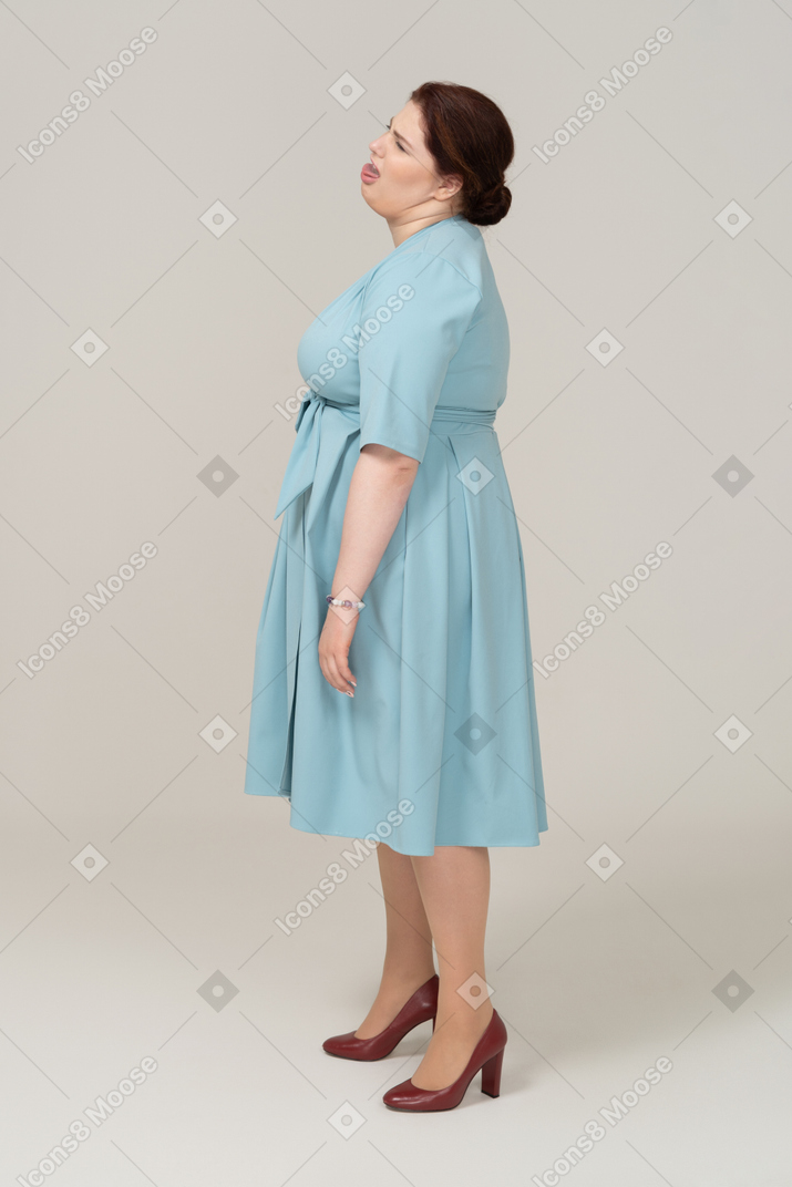Vista lateral de uma mulher de vestido azul fazendo caretas