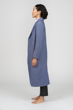 Side view of a woman in blue coat standing