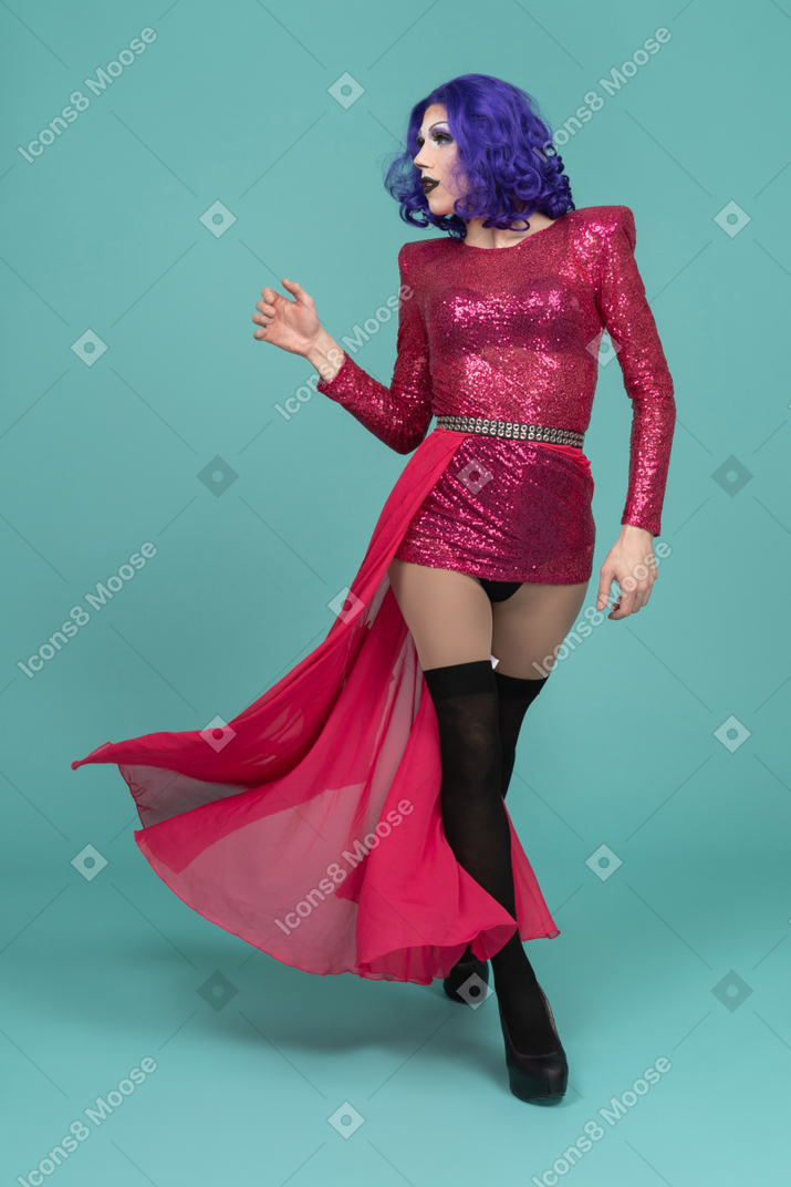 Front view of a drag queen in pink flowing skirt walking confidently