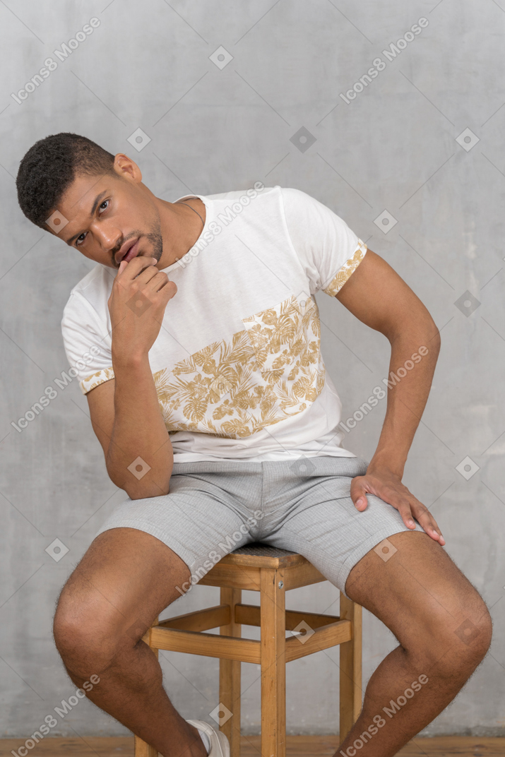 Man on stool touching chin