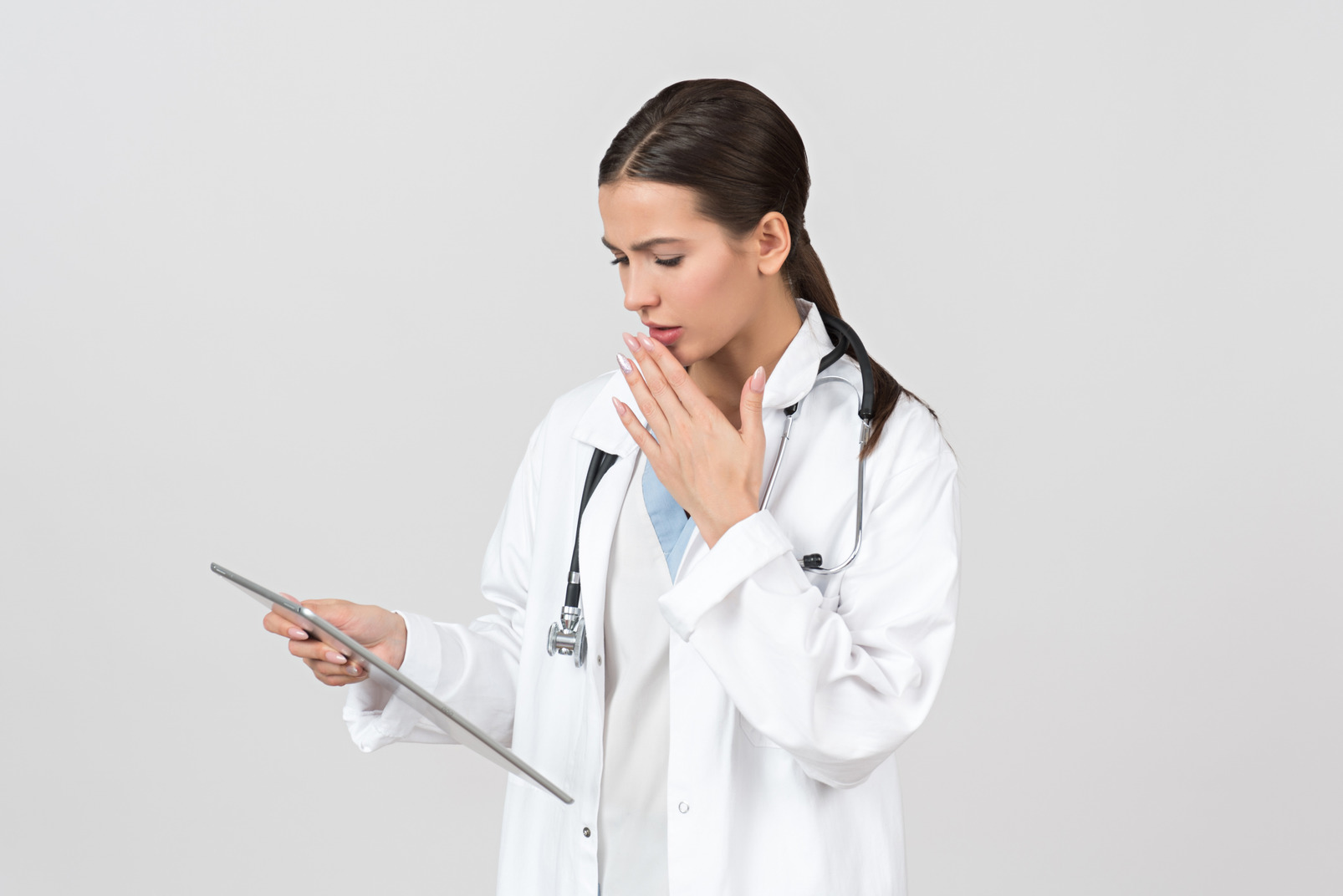 Young female doctor looking worried about info on digital tablet