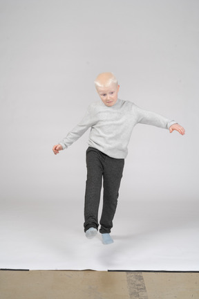 カメラに向かって歩いているカジュアルな服装の少年の正面図