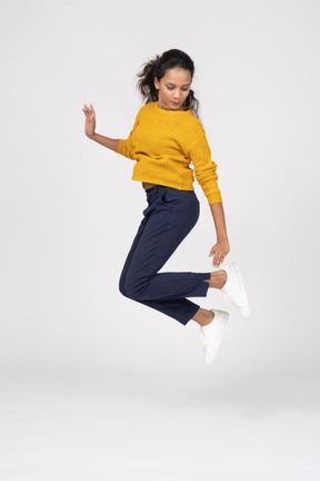 Side view of a girl in casual clothes jumping and touching her foot