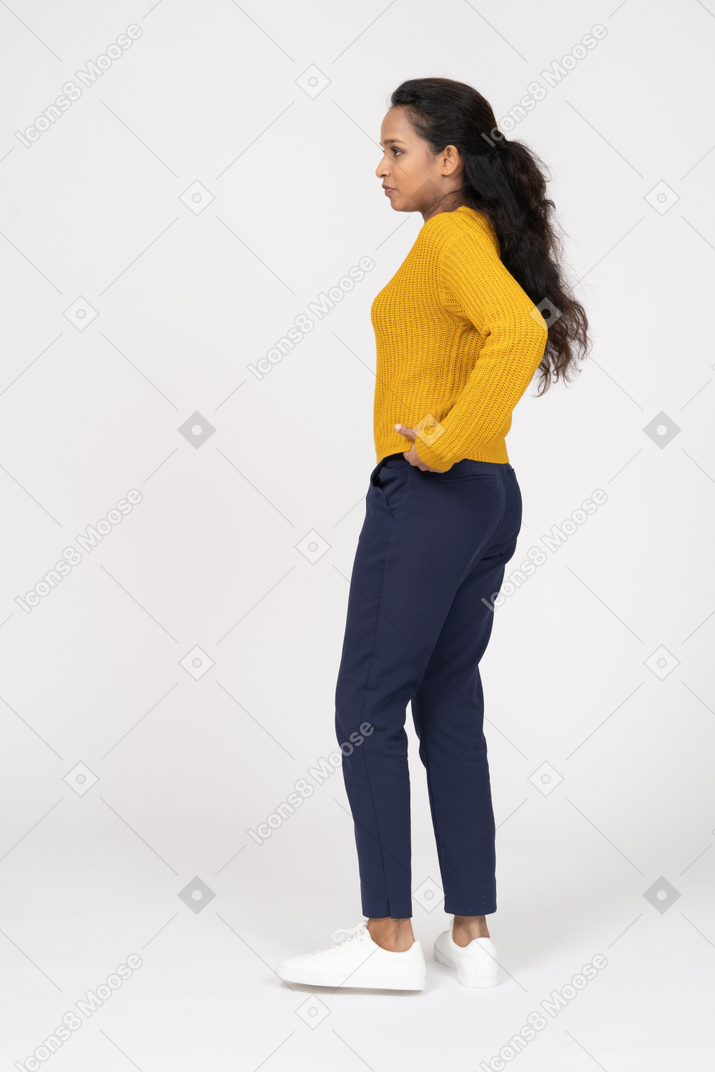 Side view of a girl in casual clothes standing with hands on hips
