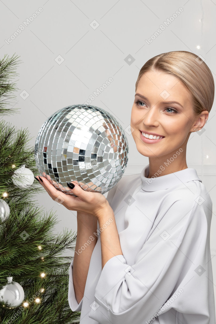 Woman in white shirt holding a disco ball for christmas party