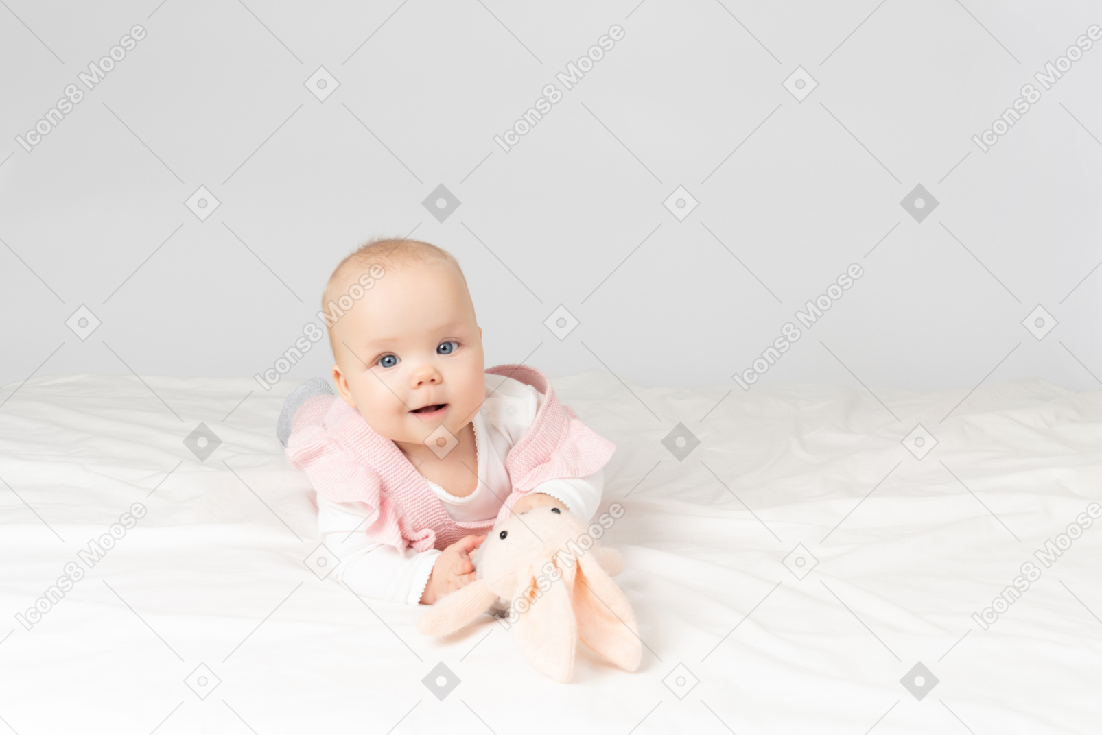 Baby girl holding toy and lying on stomach