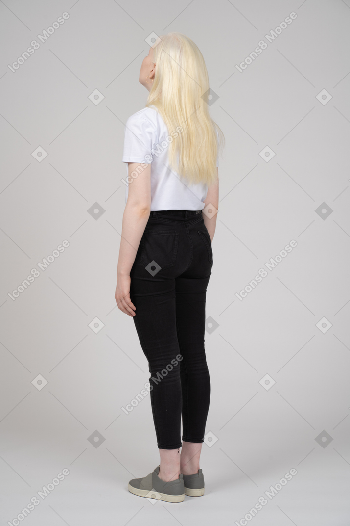 Three-quarter back view of a teenage girl with arms at sides