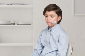 A young boy sitting in a chair with a thermometer in his mouth