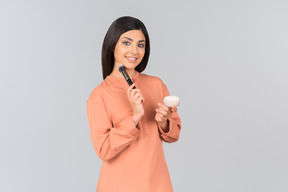 Indian woman holding face powder and powder brush