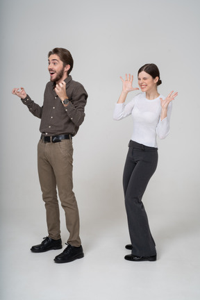 一对高兴的年轻夫妇穿着办公室服装的四分之三视图