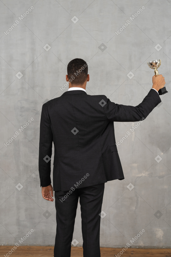 Vista posterior de un hombre sosteniendo un premio.