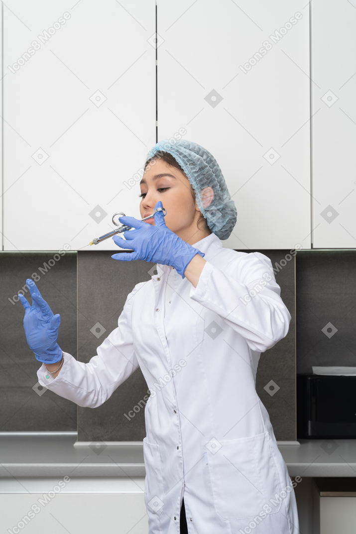 Vista frontal de una doctora levantando la mano y haciendo una inyección