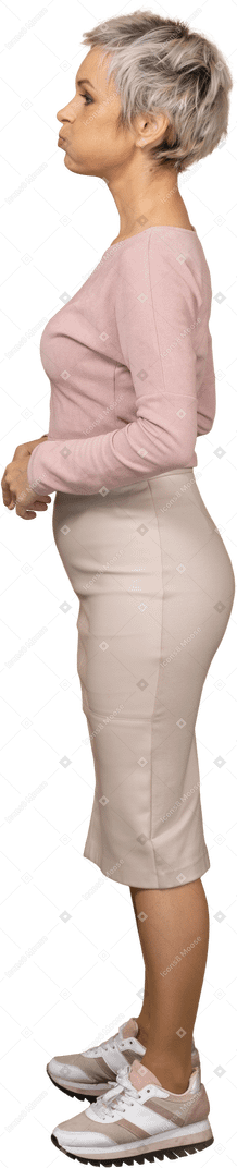 Vista lateral de uma mulher em roupas casuais com as bochechas bufantes