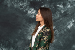 Side shot of young businesswoman standing with her eyes closed