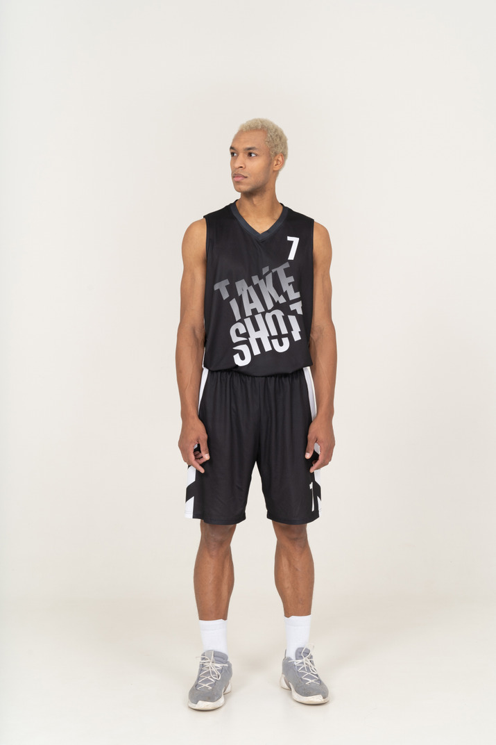 Front view of a young male basketball player standing still & looking aside