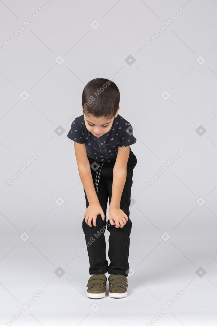 一个可爱的男孩蹲着触摸膝盖的前视图