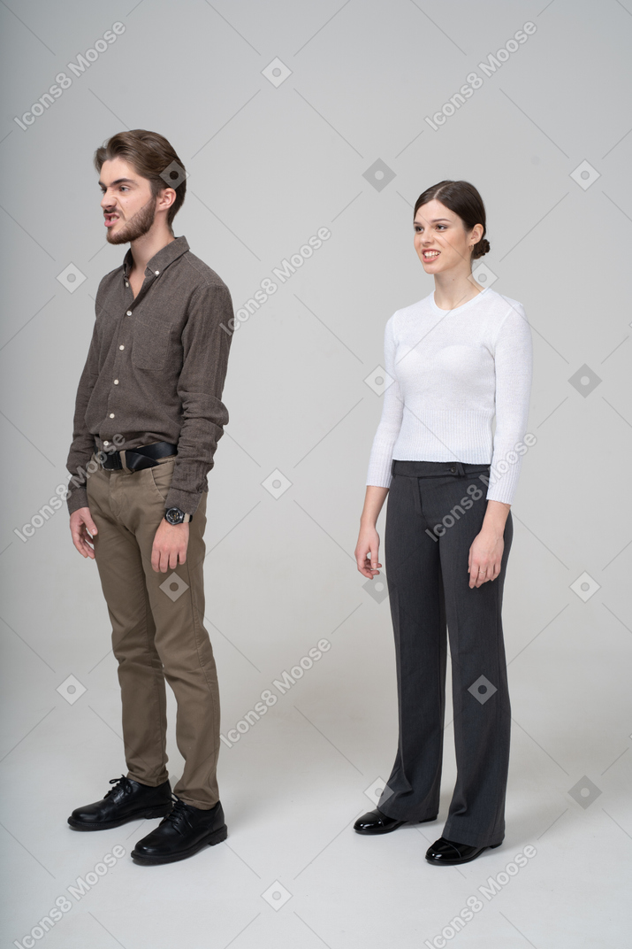 Three-quarter view of a young couple in office clothing clenching teeth