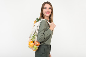 Young woman holding a string-bag with some organic food in it