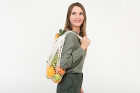 Joven mujer sosteniendo una bolsa de cadena con algo de comida orgánica