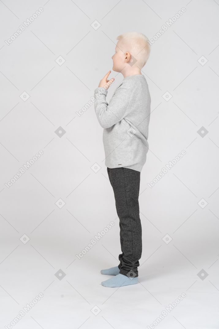 Vista lateral de un niño pequeño pensando