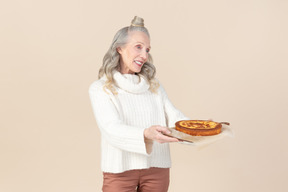 Элегантная пожилая женщина предлагает попробовать домашний пирог