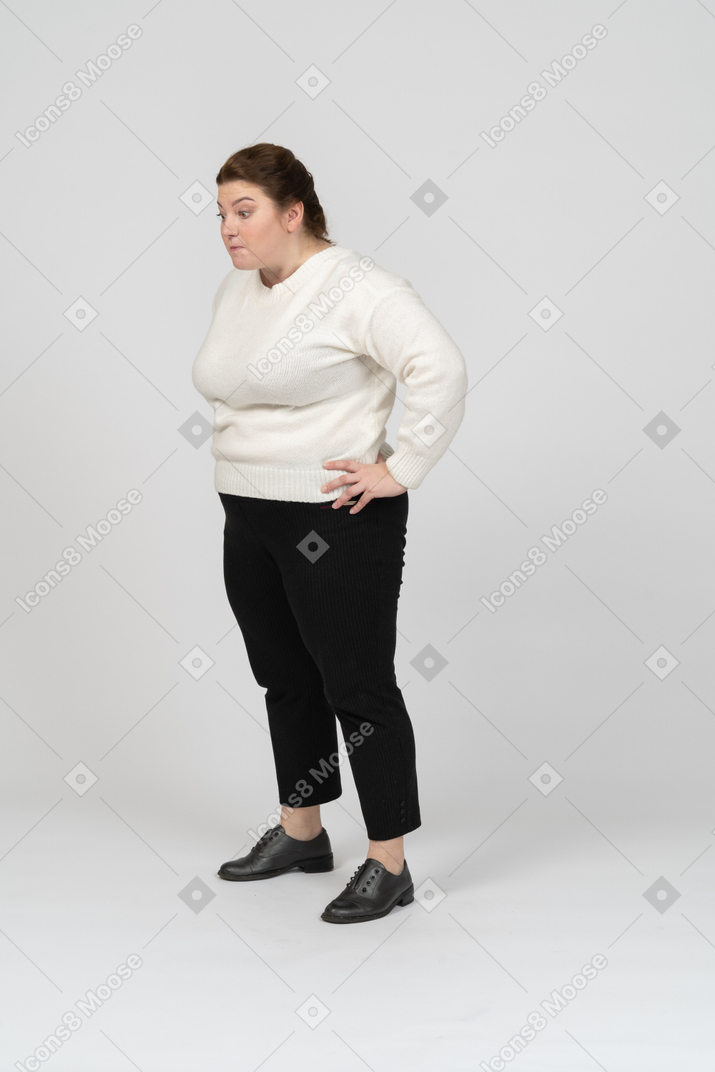 Side view of a plus size woman in casual clothes standing with hands on hips
