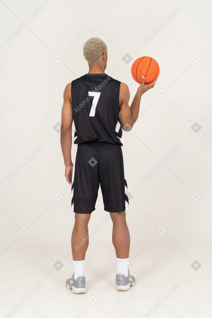 Vista posteriore di un giovane giocatore di basket maschile che tiene una palla