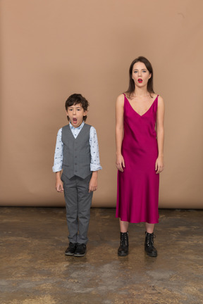 Mujer soñolienta en vestido rojo y niño en chaleco gris