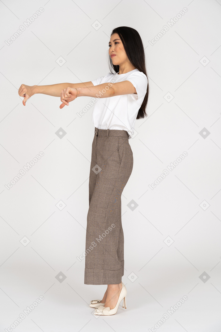 Three-quarter view of a young lady in breeches and t-shirt showing thumbs down