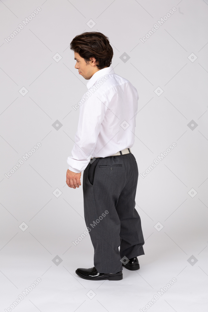 Vista traseira de três quartos de um homem em trajes formais olhando para longe