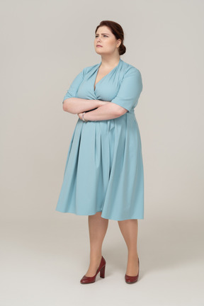 一个穿着蓝色连衣裙、双臂交叉摆姿势的女人的前视图