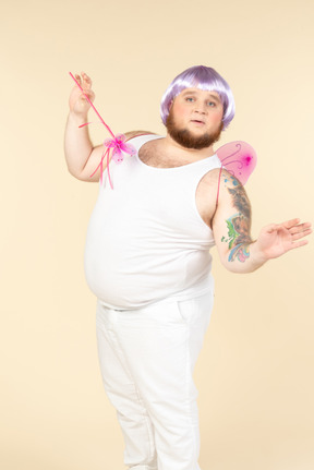 Dreamy looking young overweight man dressed as a fairy holding fairy wand