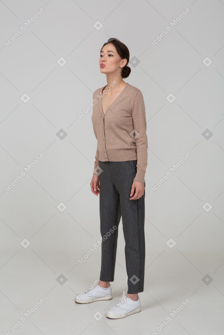 Вид в три четверти надутой молодой леди в пуловере и брюках