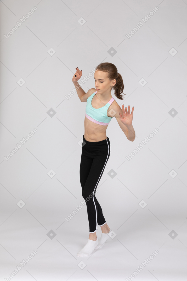 Three-quarter view of a teen girl in sportswear walking cautiously on her tiptoes