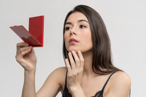 Beautiful young woman using a hand mirror